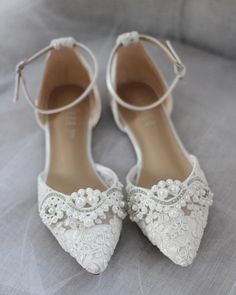 wedding shoes with pearls on them sitting on a bed