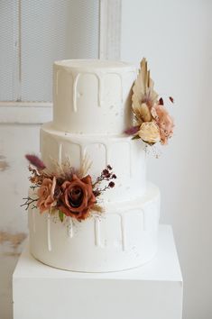 a three tiered white cake with flowers on top