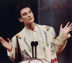 a man standing at a podium with his hands in the air and wearing a white shirt