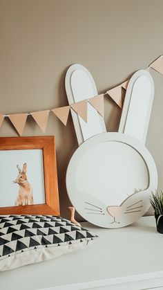 a white shelf topped with a framed photo and a bunny head on top of it