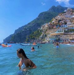 people are swimming in the ocean near some buildings