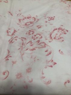 an image of a white and red bed sheet with pink flowers on the coverlet