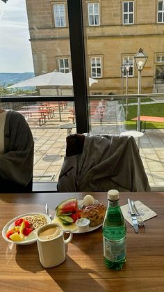 a table with food and drinks on it in front of a window overlooking a building