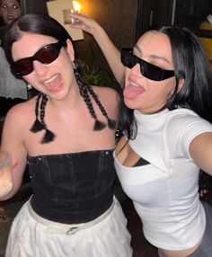 two women dressed in black and white posing for the camera with their tongue out,