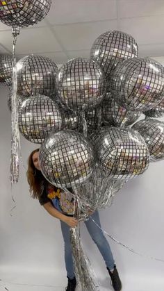 a woman standing in front of a bunch of silver balls