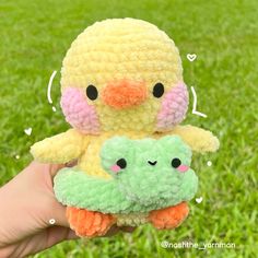 a person holding two small stuffed animals in their hands, one is yellow and the other is green