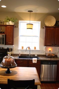 a kitchen with wooden cabinets and an island in front of a window that has lights on it