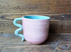 a pink and blue mug sitting on top of a wooden table