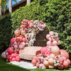 a couch covered in balloons and flowers on the grass