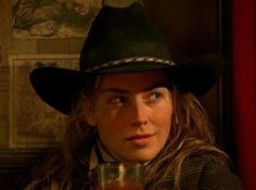 a woman wearing a cowboy hat holding a drink