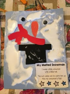 a snowman made out of paper on top of a piece of cloth with scissors