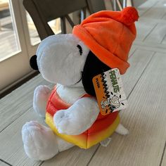 a white stuffed dog with an orange hat on it's head sitting on the floor