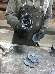 a man in overalls and gloves holding a flower on a table with other tools