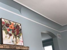 a painting is hanging on the wall above a fire place in a room with blue walls