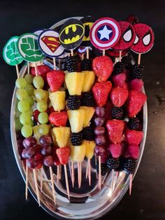 a platter filled with fruit and topped with spider - man cut out stickers