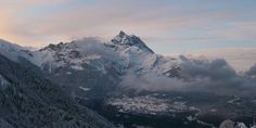 the mountains are covered in snow and clouds