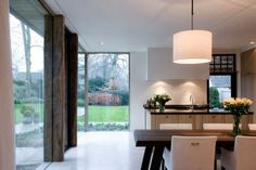 a dining room table surrounded by white chairs and an open kitchen with sliding glass doors