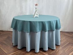 a round table with a blue cloth on it and a small flower in the center