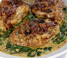 three pieces of meat with spinach and sauce in a white bowl