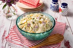 a glass bowl filled with potato salad on top of a red and white striped napkin