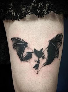 a black and white photo of a bat tattoo on the side of a woman's leg