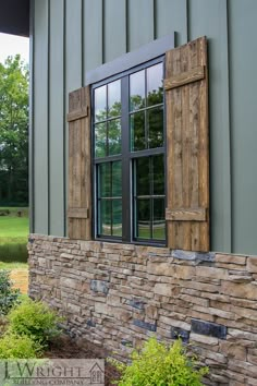 an old window with wooden shutters on the side of a stone wall in front of a green building