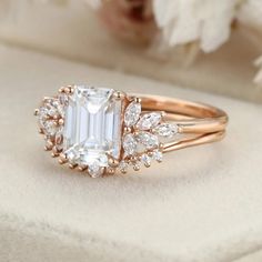 an engagement ring with a large white diamond surrounded by smaller diamonds on top of it