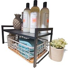 a shelf with some bottles and towels in it next to a potted plant on the floor