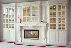 a living room with white furniture and a fire place in the middle of the room