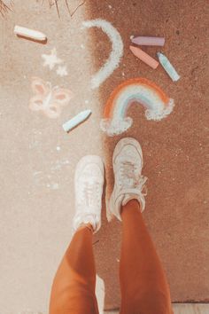 a person standing on the ground with chalk and crayons in front of them