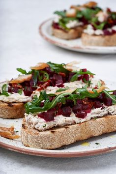 two plates that have food on them and one has bread with cheese, spinach and cranberry sauce