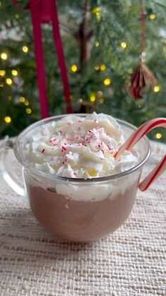 hot chocolate and marshmallows in a glass bowl with candy cane on the side