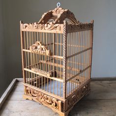 a wooden birdcage sitting on top of a wooden floor