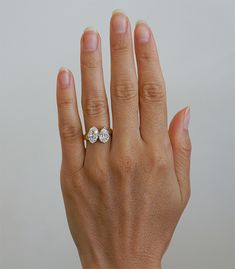 a woman's hand with an engagement ring on her left and two diamonds on the right