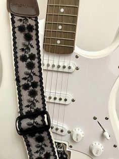 an electric guitar strap with black flowers on it, next to other guitars and strings