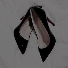 a pair of black high heeled shoes laying on top of a white bed sheet