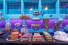 an assortment of candy and candies on display in front of a blue building at night