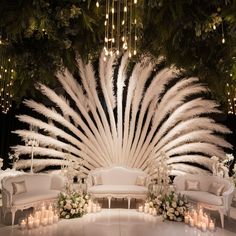 a large white peacock sitting on top of a lush green field next to candles and flowers