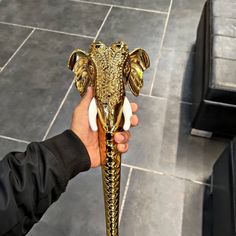 a person holding an elephant head trophy in their hand on a tile flooring area