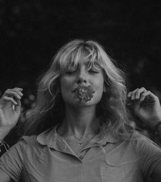 a black and white photo of a woman with food in her mouth