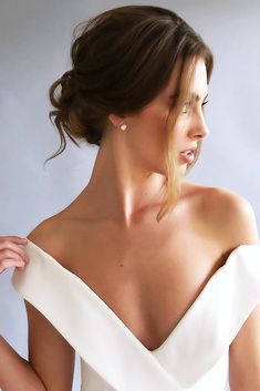 a woman in a white dress with her hair pulled back and wearing earrings on her head