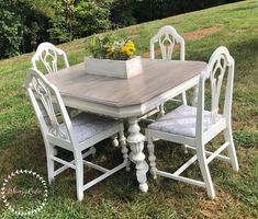 a wooden table and four chairs sitting in the grass