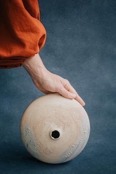 a person reaching for a vase on a blue surface with their hand over the top