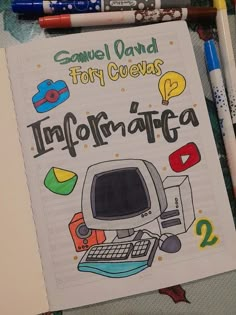 a notebook with an image of a computer on it, surrounded by crayons and markers