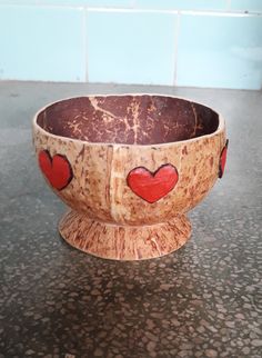 a wooden bowl with red hearts painted on it sitting on a counter top next to a tile wall