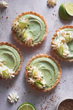 four small pies with lime and whipped cream on top, surrounded by other toppings