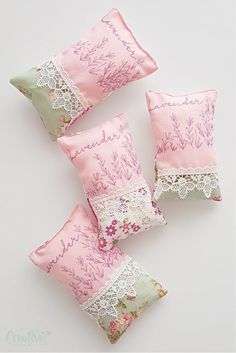 four pink pillows with lace trim on them sitting next to each other in front of a white background