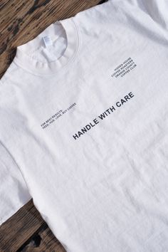 Our "Handle with Care" heavyweight cotton shirt is the perfect addition to your wardrobe. Made with high-quality materials and featuring a bold and stylish design, this shirt is both comfortable and durable. The neutral color is easy to pair with a variety of different outfits, making it a versatile choice for any occasion. Marketing Shirts Design, Business Tshirt Design Ideas Logo, Back Shirt Design Ideas, T Shirt Colors Ideas, Edgy T Shirt Design, Luxury Tshirt Design, Clothing Designer Aesthetic, Tshirt Aesthetic Design, Cool Shirts Aesthetic