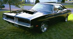 a black muscle car parked in the grass