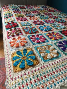 a crocheted granny blanket with flowers on the top and bottom is laying on a bed